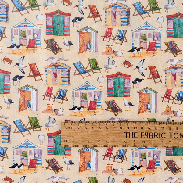 A repeating beach-themed pattern featuring colorful beach huts, striped deck chairs, seagulls, crabs, and small animals on a pale yellow background.