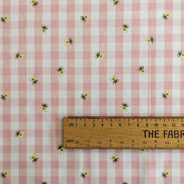 Bee and floral fabric on pink and white gingham with ruler for scale.