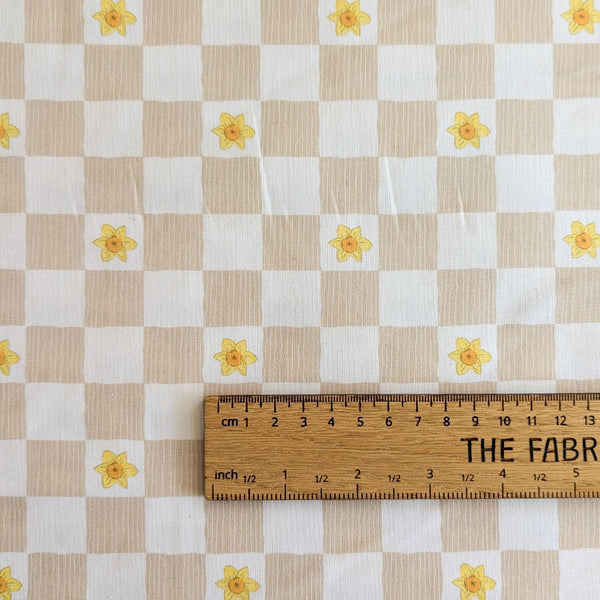 Cream and beige gingham fabric with yellow daffodil flowers with ruler for scale.