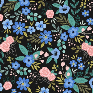 Bold floral fabric with pink roses, blue blossoms, and green and gold foliage on a dark background.