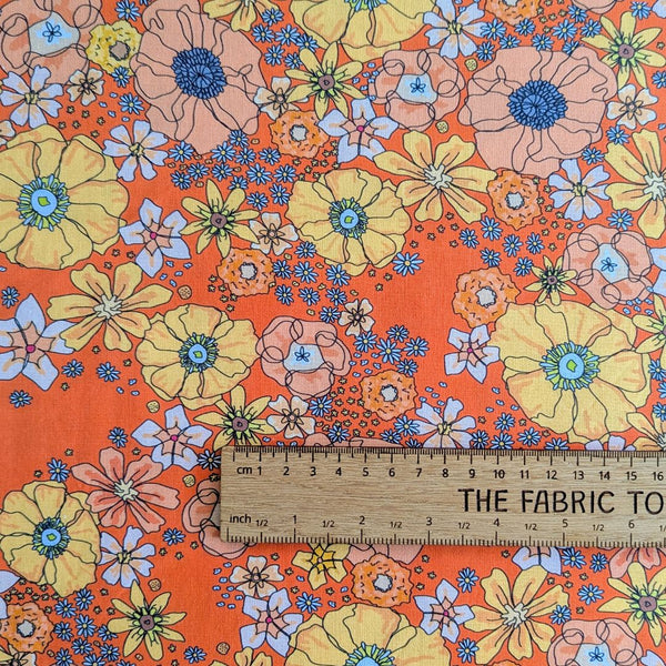 Rainbow Garden fabric: Orange floral design with retro feel with ruler for scale.