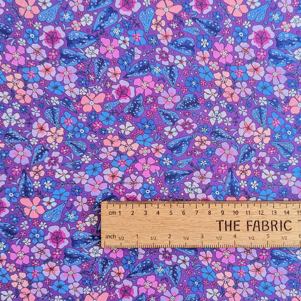 Rainbow Garden fabric: Pink, blue, and purple flowers on a dark purple background with ruler for scale.